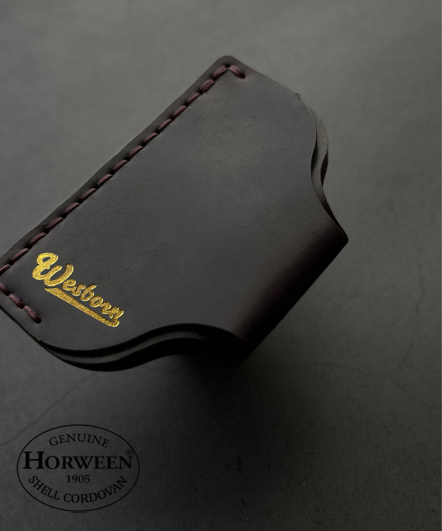 Dark leather wallet with Wesborn branding on a gray background