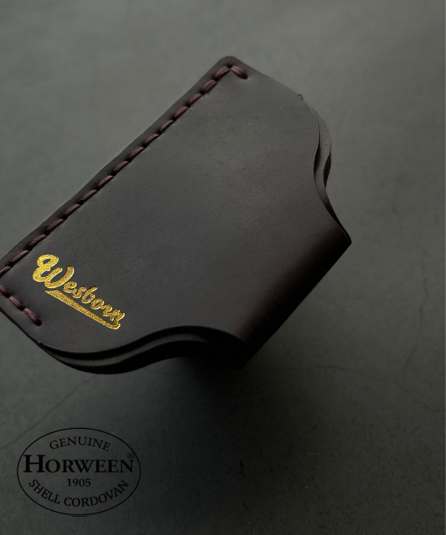 Dark leather wallet with Wesborn branding on a gray background