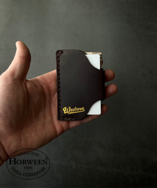 Hand holding a leather wallet with 'Horween' branding against a dark background
