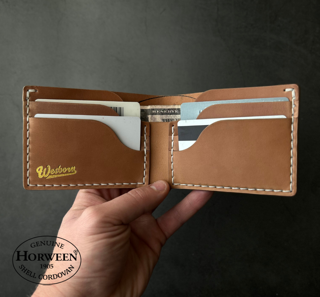 Hand holding a brown leather wallet with visible stitching on a dark background